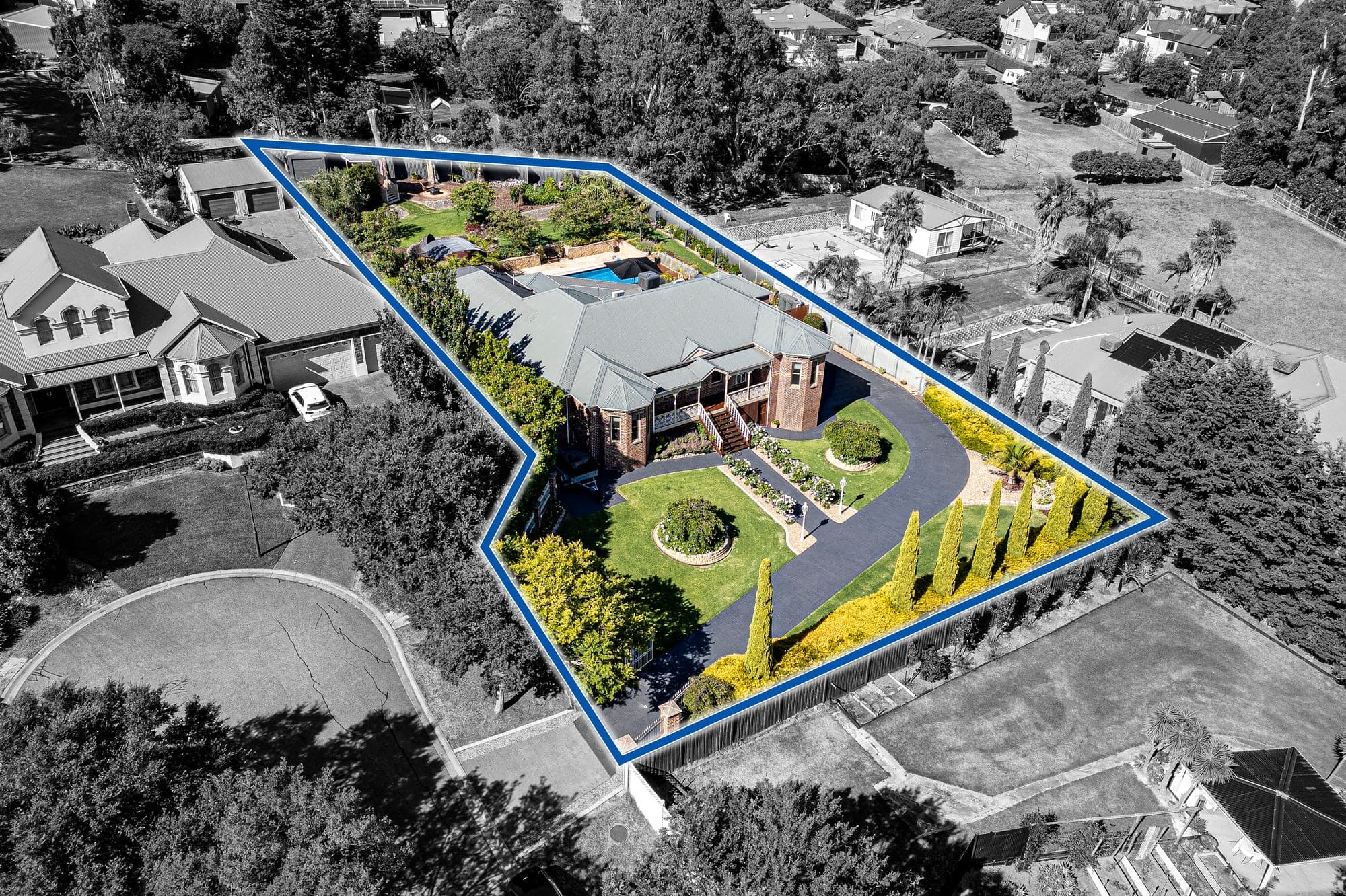 Aerial from the front, a landscaped block outlined in blue with the surrounding houses dropped back to grey