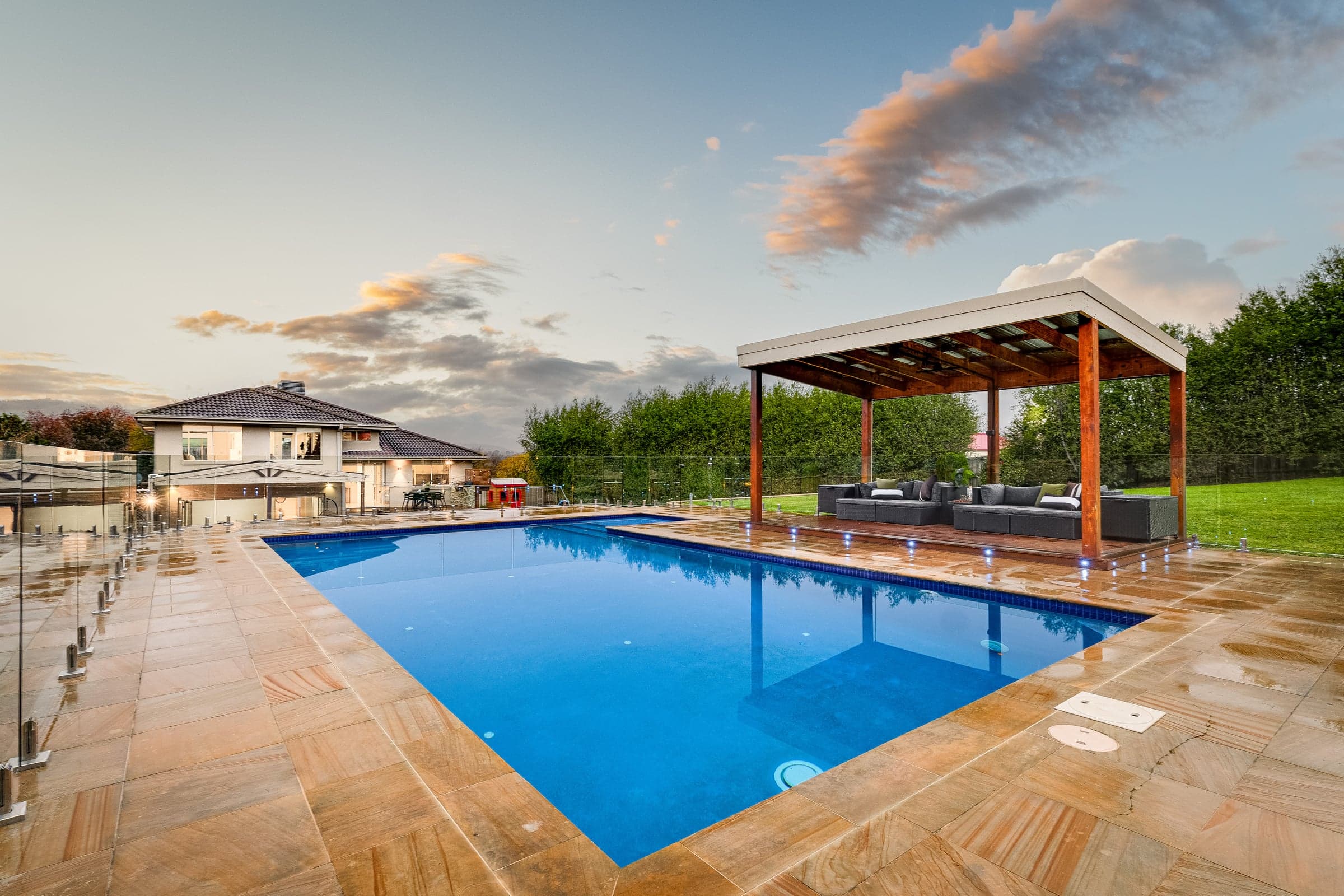 Pool and pitched pavilion at dusk with the house lit behind, Lysterfield