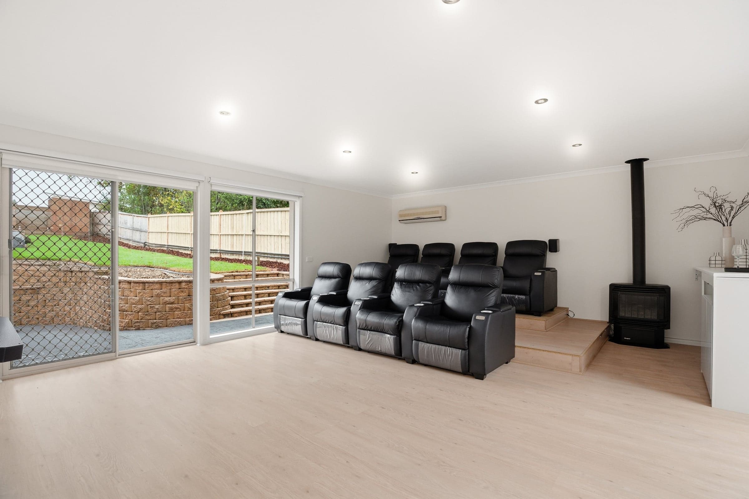 Home theatre with tiered recliners beside a wood fire