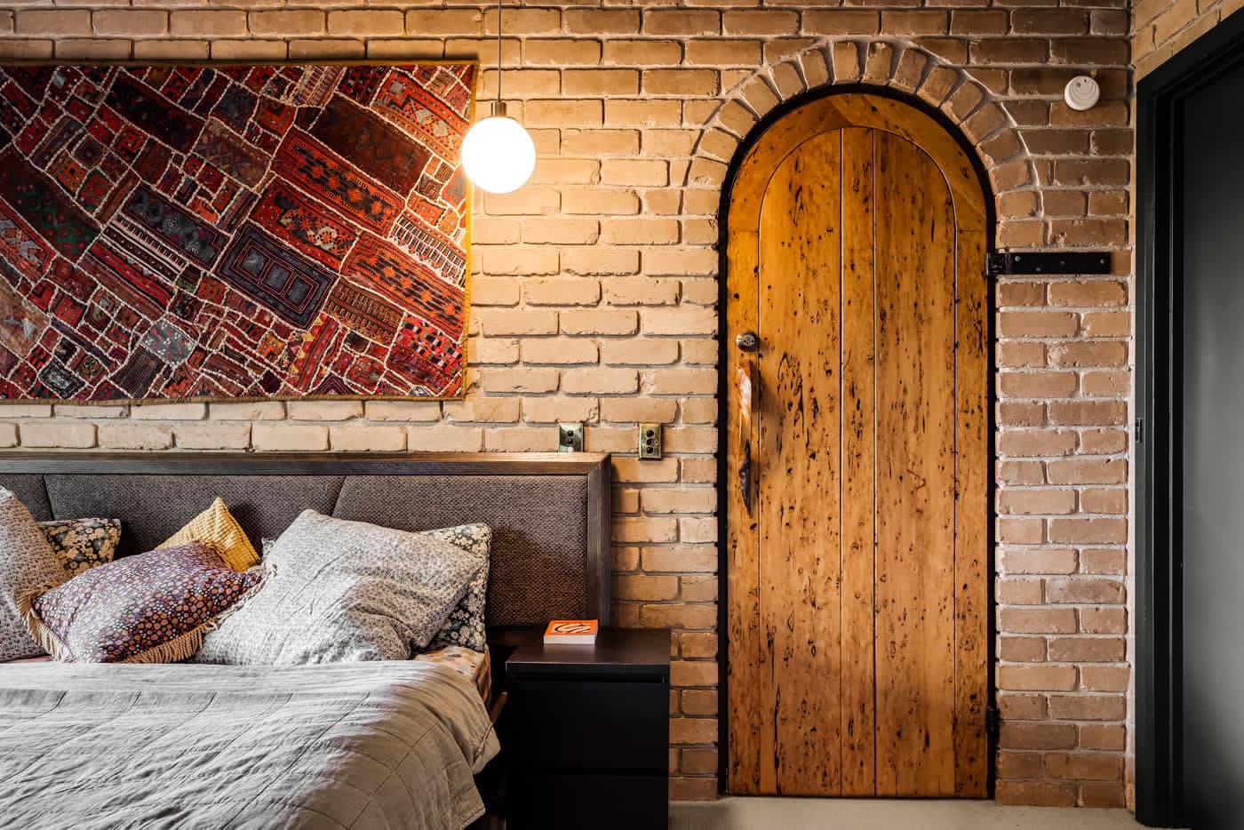 Bedroom with an arched timber door set into brickwork