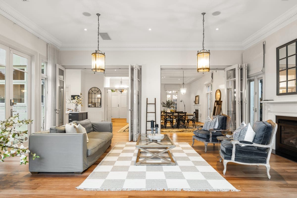 Living room with a checkerboard rug and hanging lanterns, opening through to the dining room beyond
